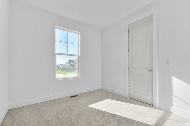 5644 Ibis Road Tooele, UT 84074 - Photo 8 of 19 Carpeted room with a double-pane window, white trim, and a paneled interior door