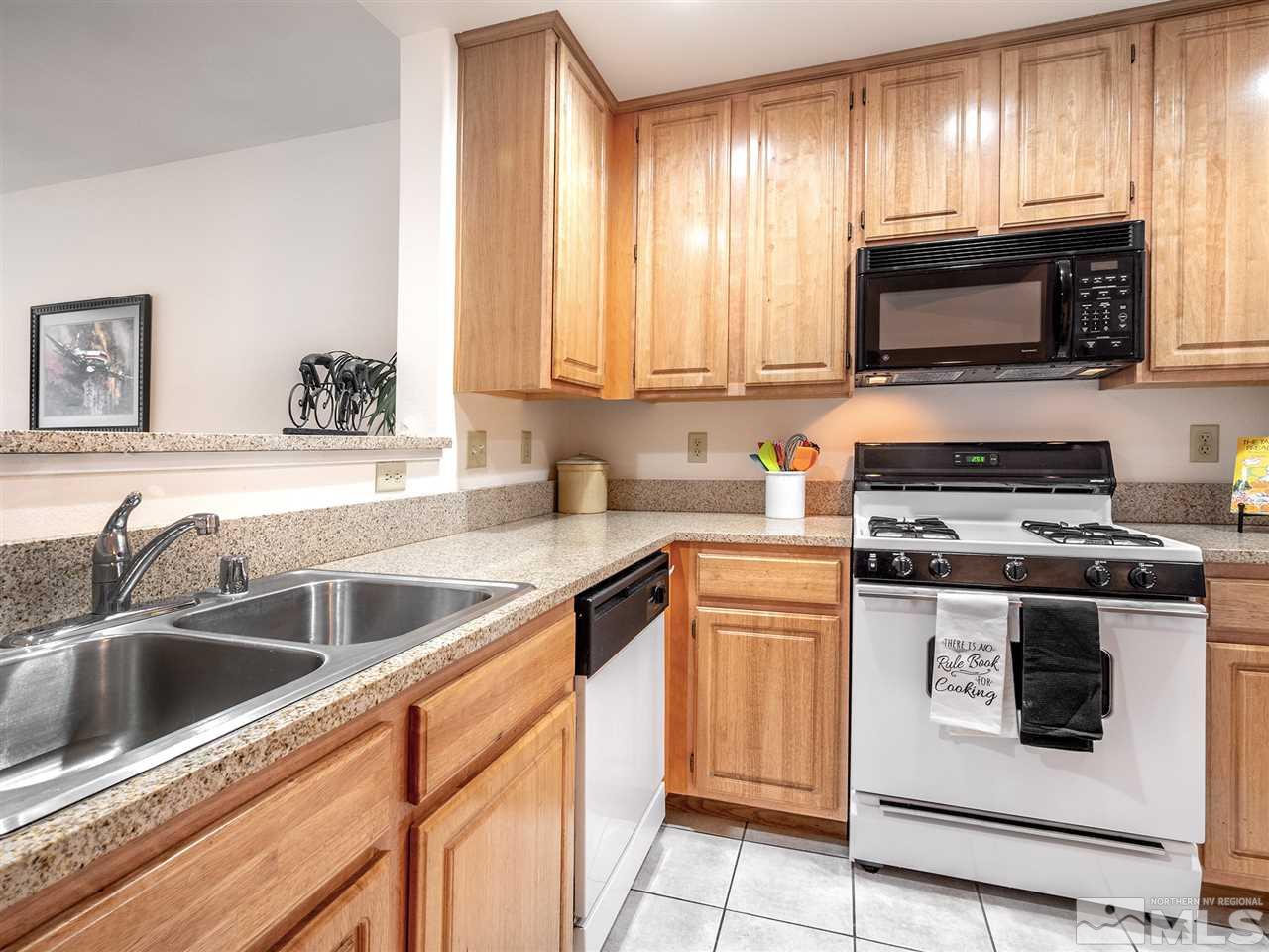 900 South, Unit 3413 Reno, NV 89521 - Photo 9 of 21 a kitchen with stainless steel appliances granite countertop a sink a stove a microwave and wooden cabinets