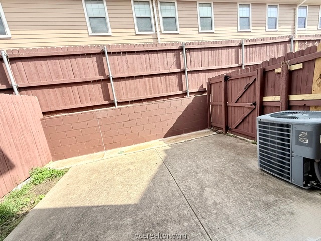 1000 Spring Loop, Unit 1806 College Station, TX 77840 - Photo 10 of 33 Paved patio area featuring a stained wood privacy fence and a brick retaining wall