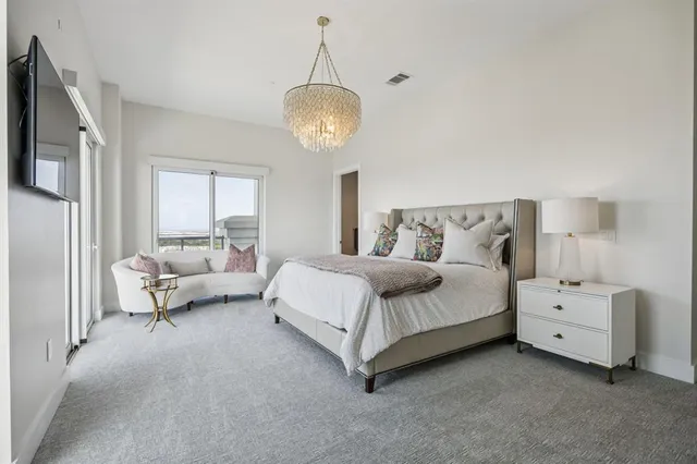 a spacious bedroom with a bed and a chandelier