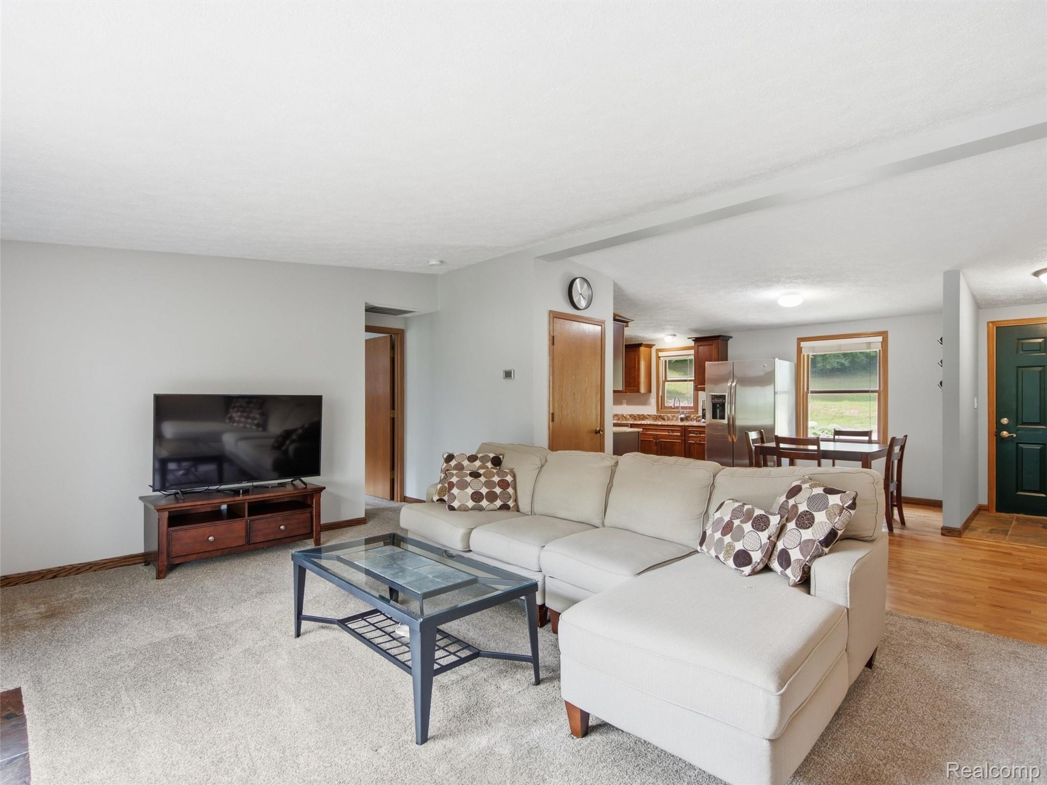5003 Mason Road Howell, MI 48843 - Photo 6 of 59 Open-concept living area with light gray walls, carpet flooring, and wood-finish trim