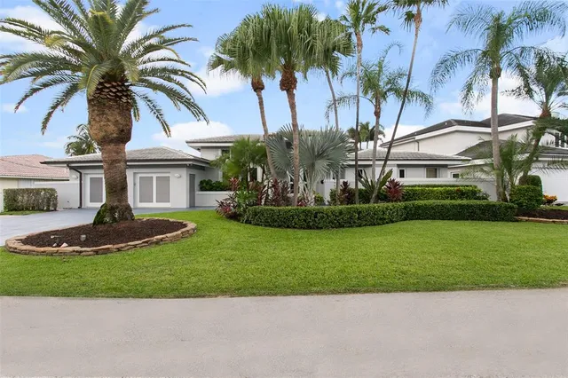 a front view of a house with a garden and palm trees