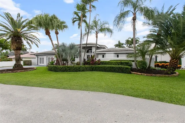 a front view of house with small garden and palm trees
