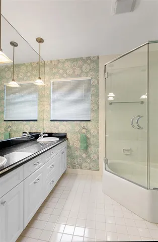 a bathroom with a granite countertop sink a mirror and shower