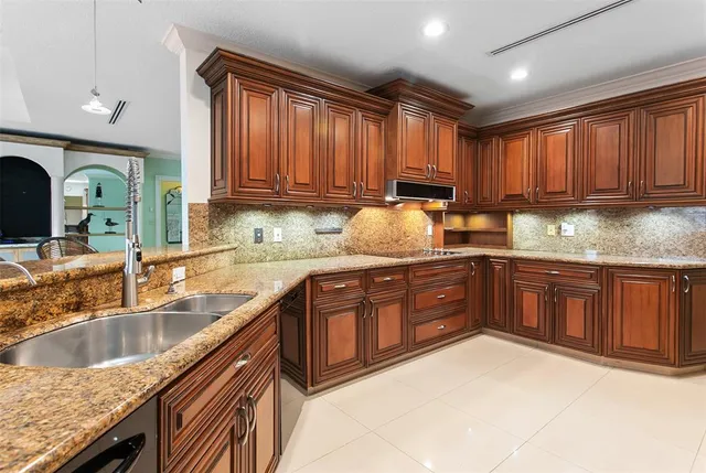a kitchen with granite countertop a sink dishwasher stove and cabinets with wooden floor