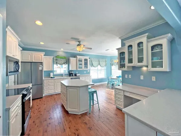 a kitchen with stainless steel appliances granite countertop a refrigerator a sink dishwasher a stove and white countertops with wooden floor