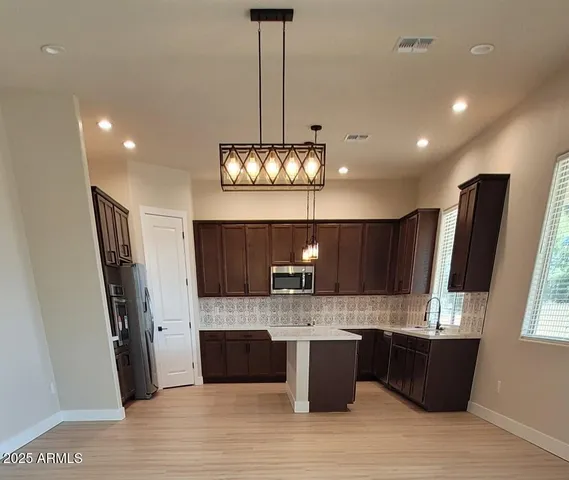 a large kitchen with granite countertop a refrigerator and a wooden floor