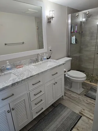 a bathroom with a granite countertop toilet sink and mirror