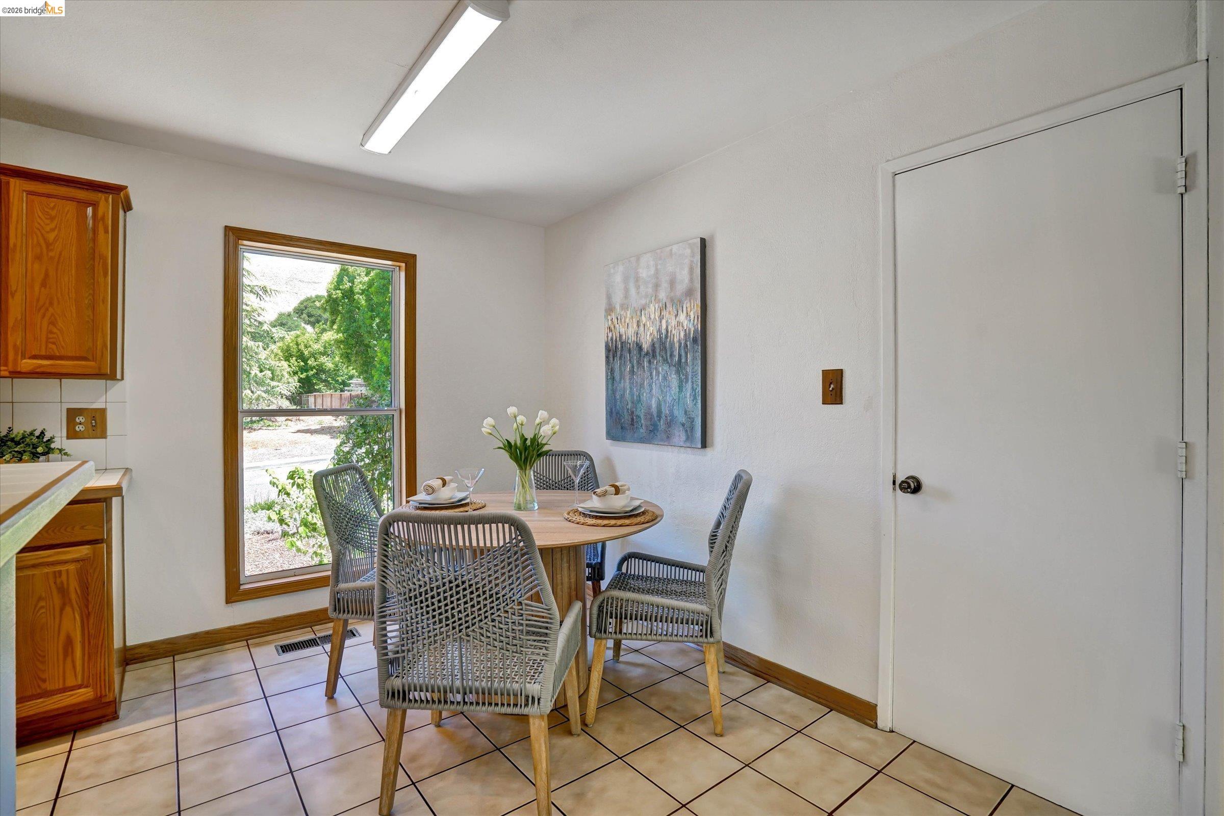 2826 Wright Avenue Pinole, CA 94564 - Photo 16 of 70 Kitchen dining area featuring a window with exterior greenery, tile flooring, wood cabinetry, and a white interior door
