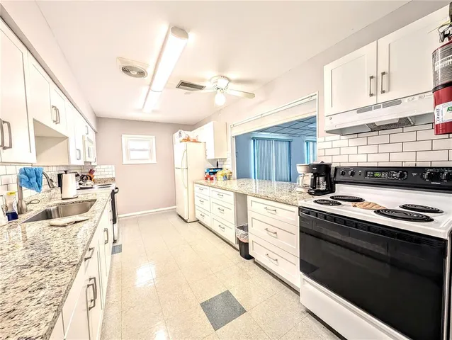 a kitchen with granite countertop white cabinets white appliances a sink and a counter space