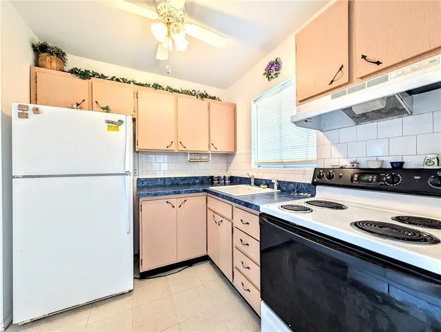 a kitchen with a refrigerator a stove a sink and white cabinets