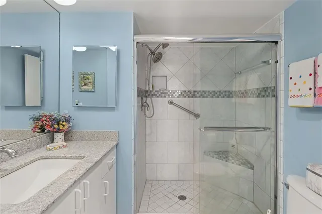 a bathroom with a granite countertop shower sink vanity and mirror