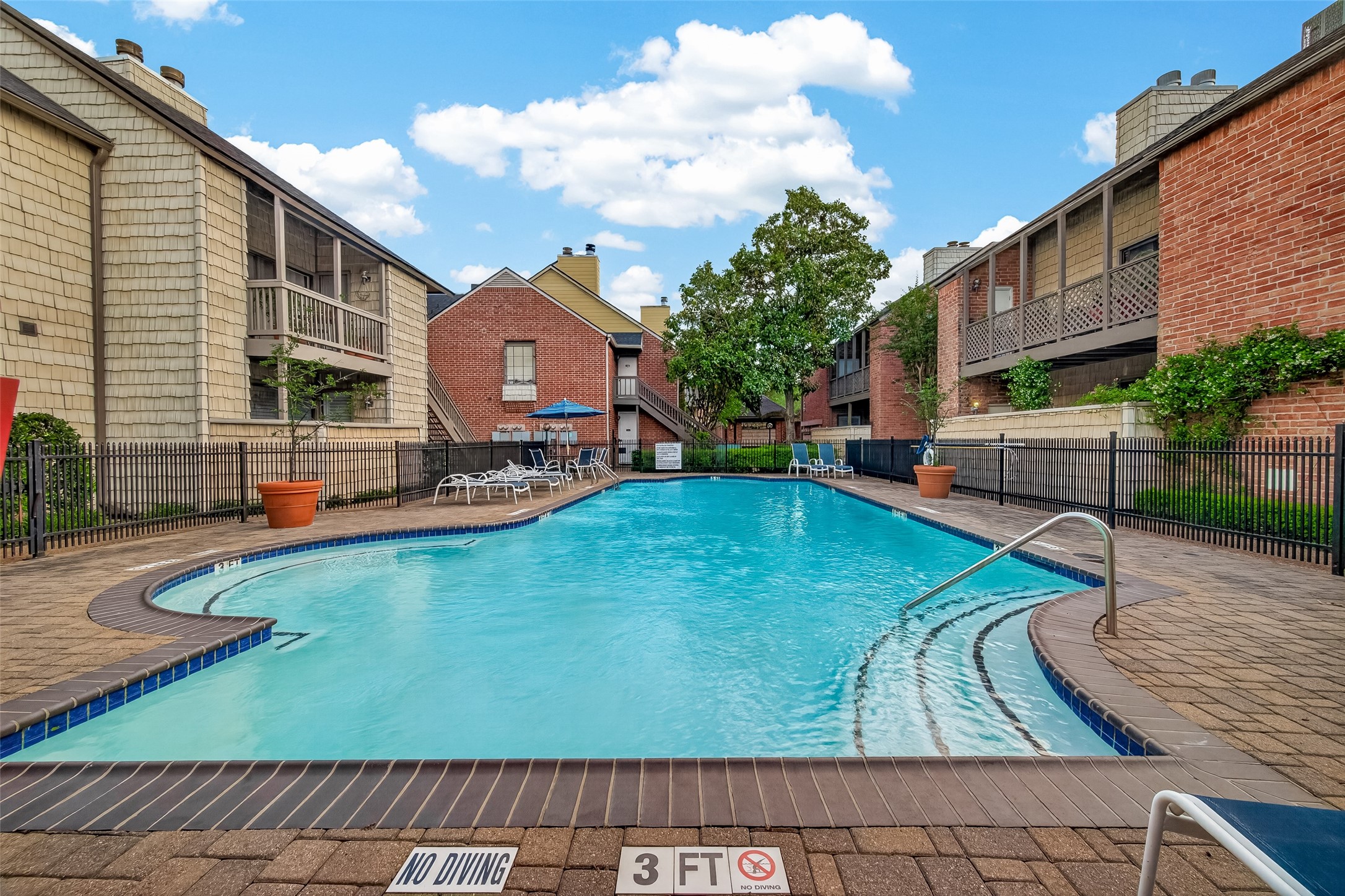2829 Timmons Lane, Unit 144 Houston, TX 77027 - Photo 33 of 41 Charming community pool area. The pool is well-maintained with lounge chairs and umbrellas, set in a landscaped courtyard, creating an inviting spot for relaxation.