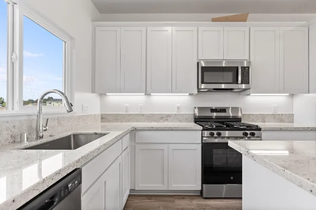 a kitchen with stainless steel appliances granite countertop a sink stove and microwave