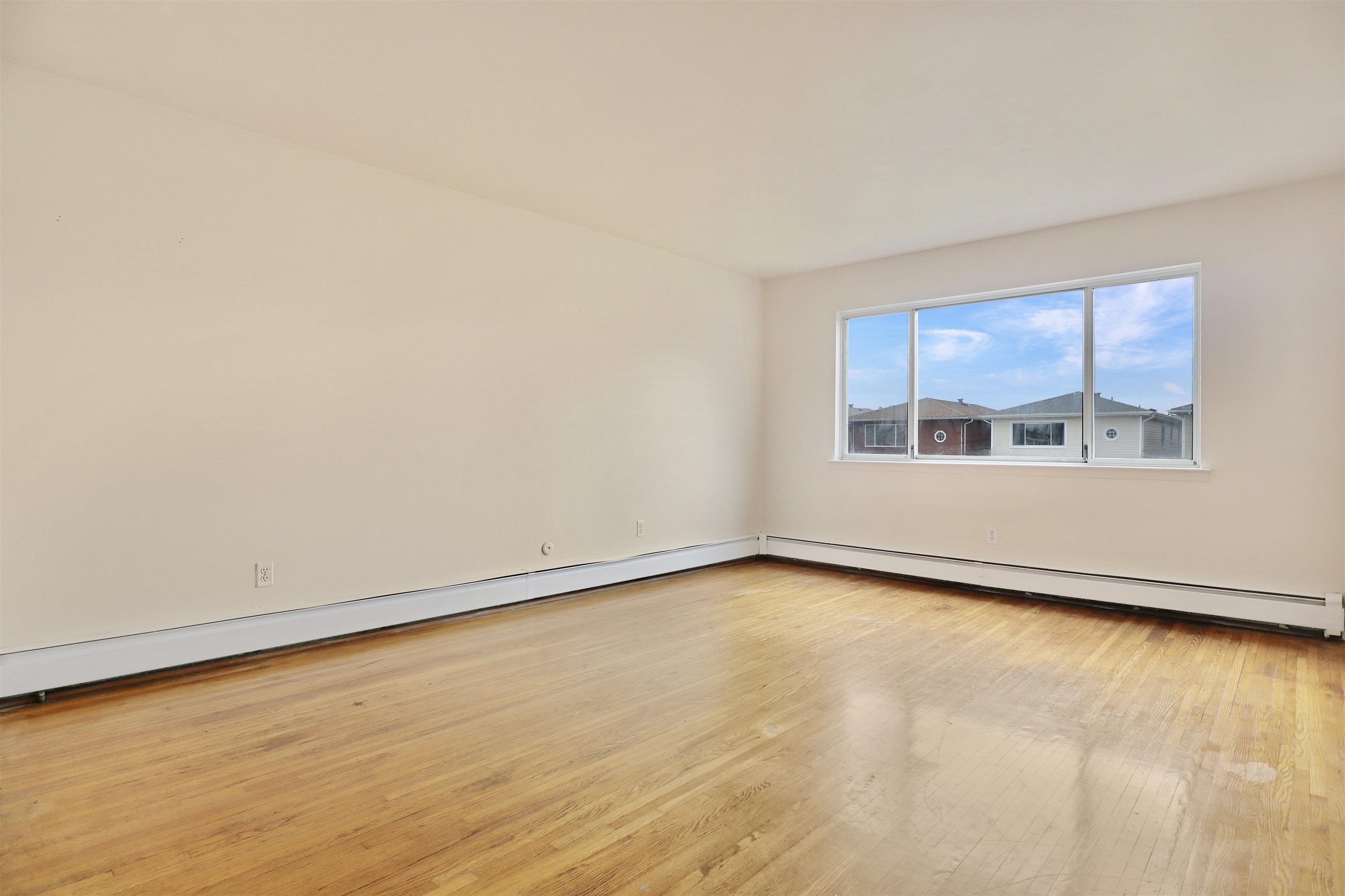 711 Bergen Street, Unit 2 Harrison, NJ 07029 - Photo 6 of 13 a view of an empty room with a window and wooden floor
