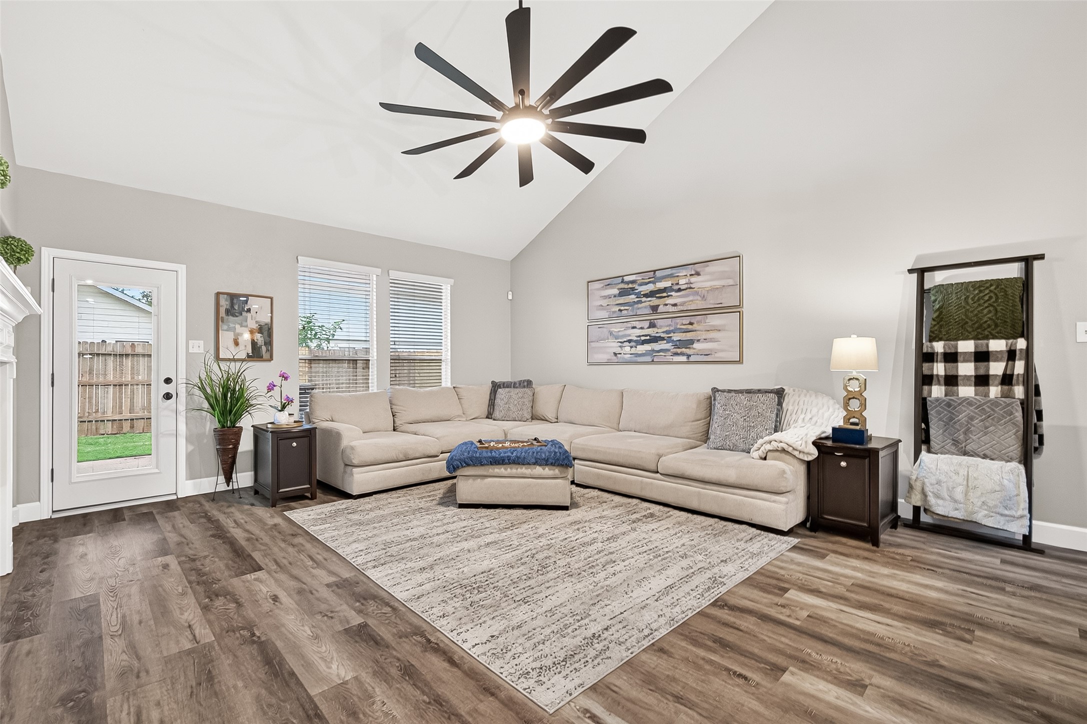 7415 Riven Oaks Court Cypress, TX 77433 - Photo 19 of 42 A second view of the expansive living room showcases the dramatic high ceilings, cozy fireplace, and oversized windows that fill the space with natural light, while offering seamless access to the backyard and primary bedroom.