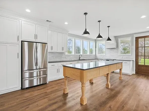 a kitchen with stainless steel appliances granite countertop a sink a refrigerator and a wooden floor