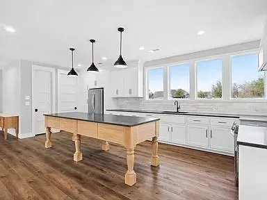 a kitchen with stainless steel appliances granite countertop a sink cabinets and wooden floor