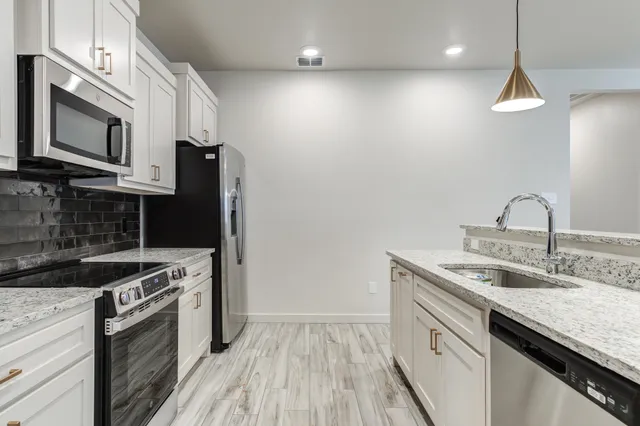 a kitchen with stainless steel appliances granite countertop a sink a stove and a refrigerator