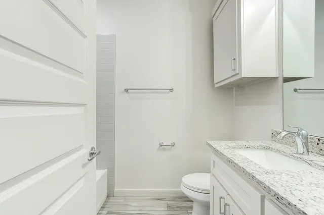a bathroom with a granite countertop sink a toilet and bathtub