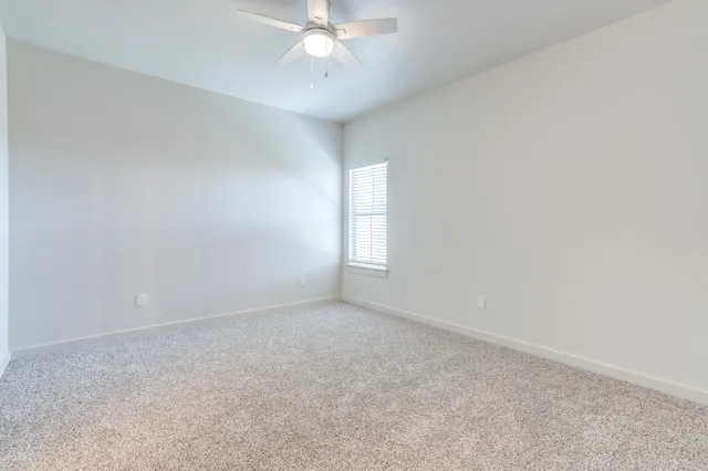 an empty room with a window and chandelier fan