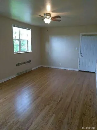 an empty room with wooden floor chandelier fan and windows