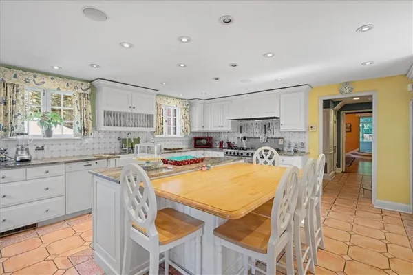 a kitchen with stainless steel appliances granite countertop a table chairs sink and cabinets