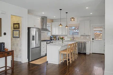 a kitchen with stainless steel appliances granite countertop a refrigerator a sink and a stove