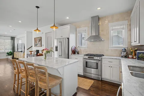 a kitchen with stainless steel appliances kitchen island granite countertop a stove a sink and a white cabinets