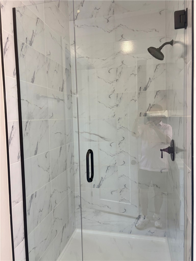 854 Perkins Creek Road Seneca, SC 29678 - Photo 16 of 34 Elegantly veined stone tile wraps this walk-in shower behind a seamless glass door.