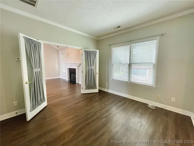 an empty room with wooden floor fireplace and windows