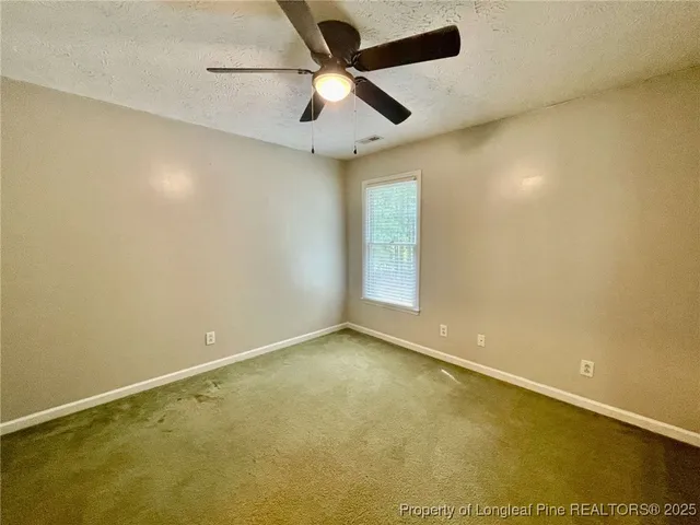 an empty room with a ceiling fan and window