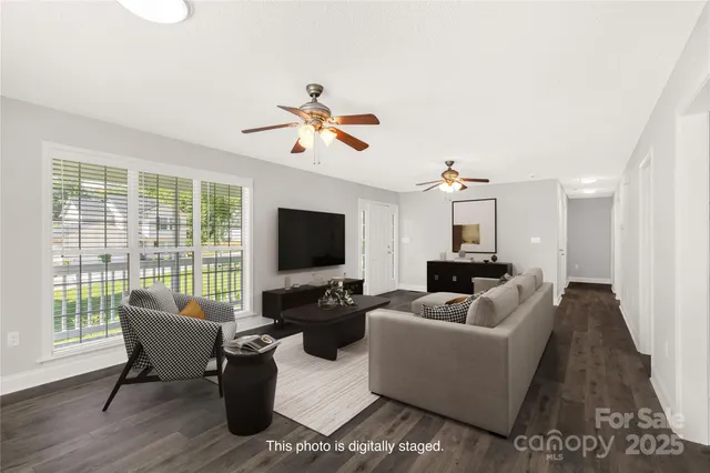a living room with furniture floor to ceiling window hardwood floor and a flat screen tv