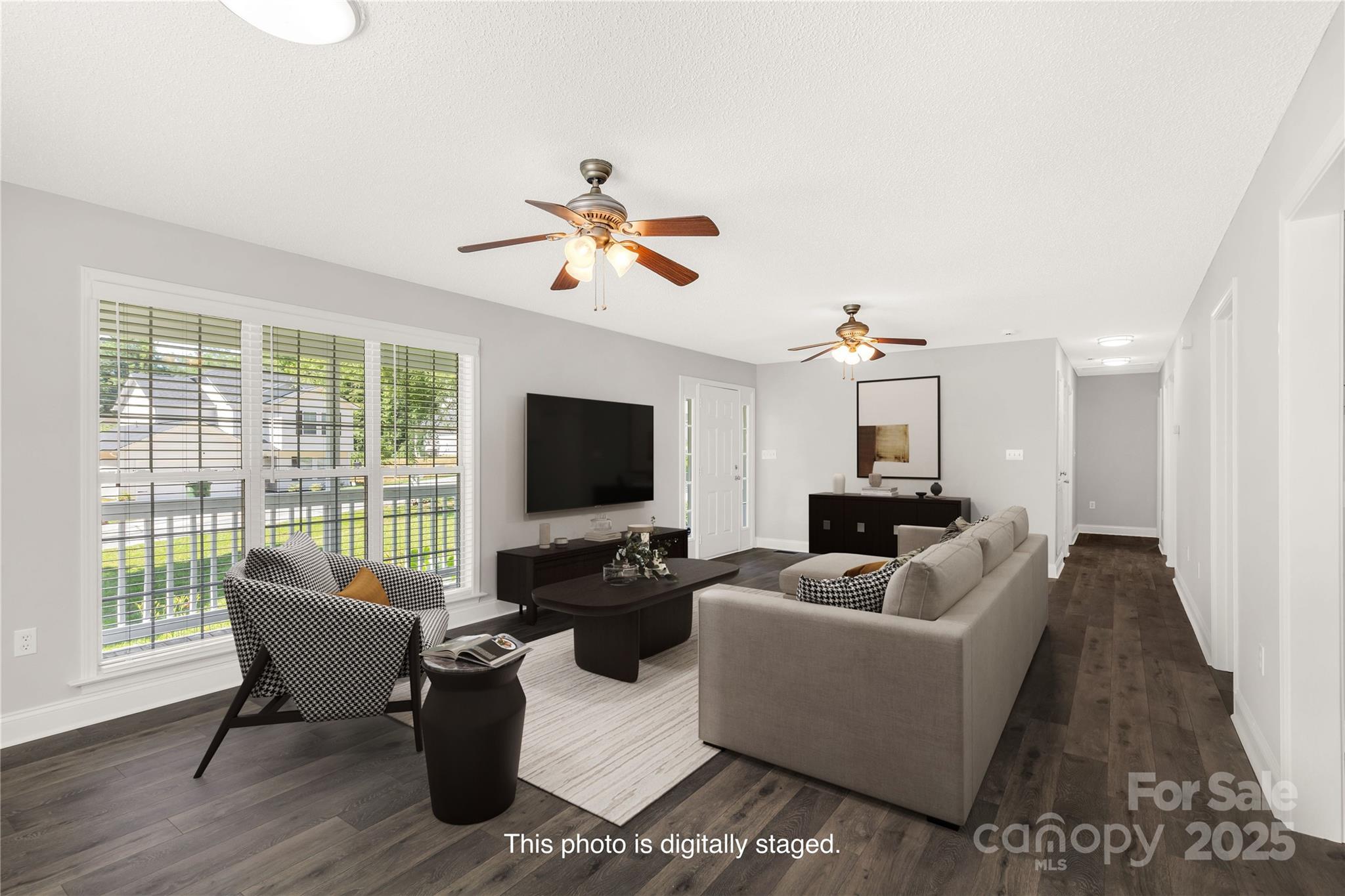 a living room with furniture floor to ceiling window hardwood floor and a flat screen tv