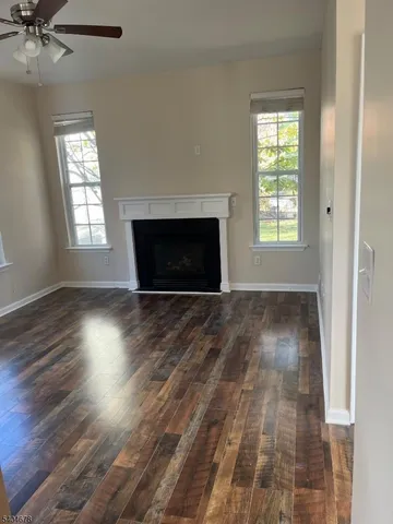 an empty room with wooden floor a fireplace and windows