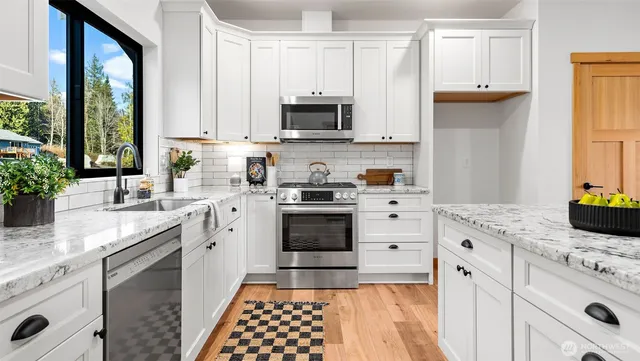 a kitchen with stainless steel appliances white cabinets and a stove top oven
