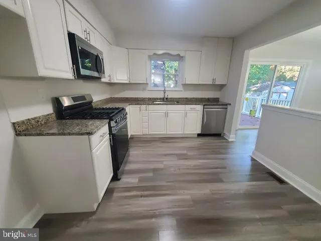 a kitchen with stainless steel appliances granite countertop a stove a sink and a microwave