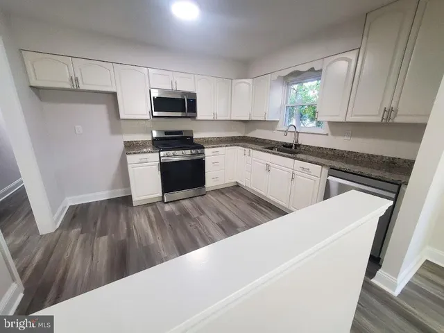 a kitchen with granite countertop a refrigerator stove top oven and sink