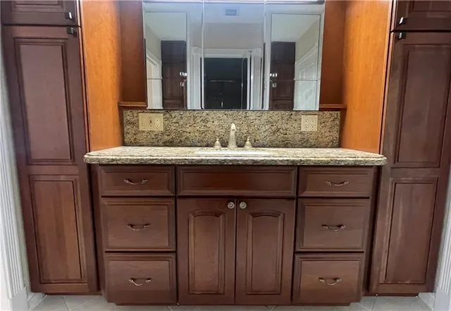 a bathroom with a granite countertop sink and a mirror