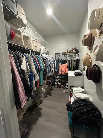 a view of walk in closet with clothes and shoes