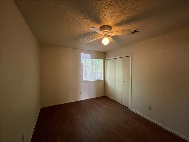 an empty room with wooden floor fan and windows
