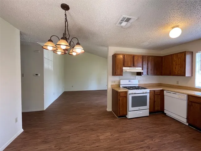 a kitchen with stainless steel appliances granite countertop a sink dishwasher a stove and a refrigerator