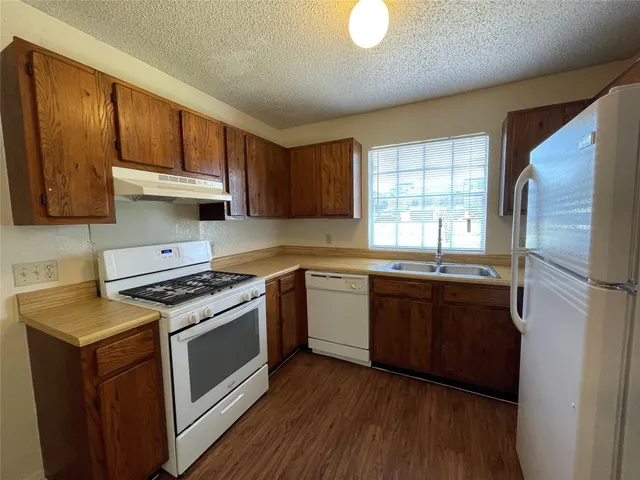 a kitchen with granite countertop wooden floors appliances and sink