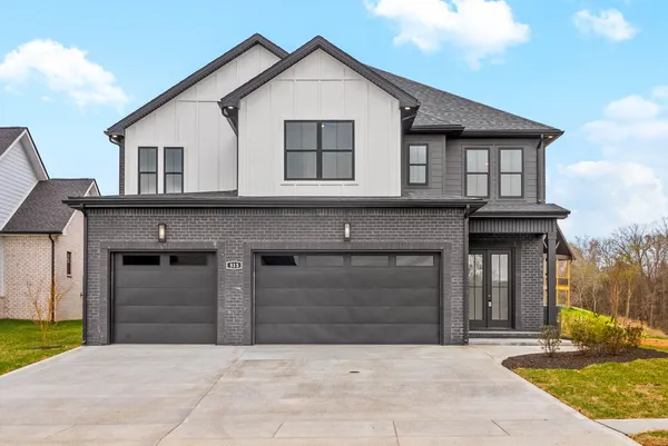a front view of a house with yard and parking