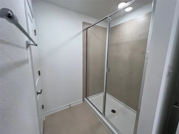 a bathroom with a glass shower door and a window