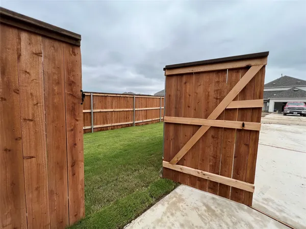a view of backyard with small cabin and wooden fencing