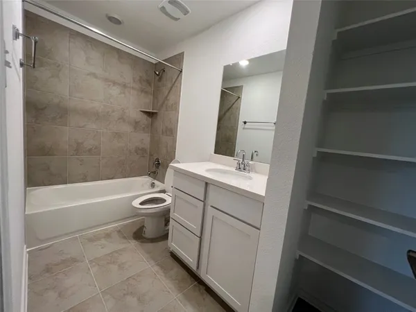 a bathroom with a granite countertop bathtub shower sink vanity and toilet