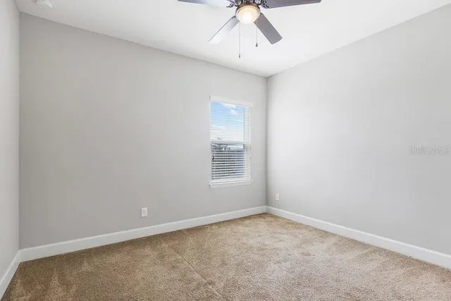 an empty room with ceiling fan and window