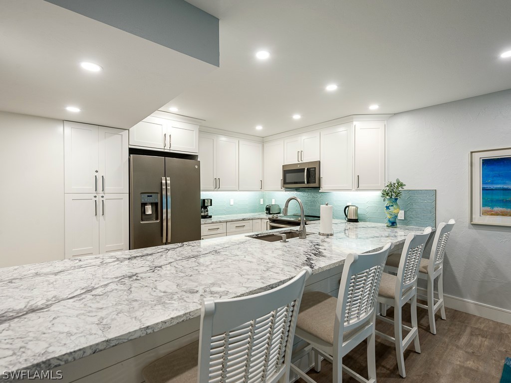 760 Sextant Drive, Unit 732 Sanibel, FL 33957 - Photo 14 of 35 a kitchen with stainless steel appliances granite countertop a table chairs sink refrigerator and microwave