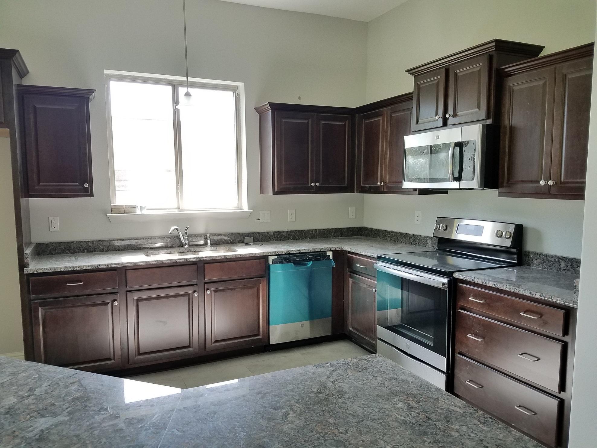 2399 Cove Road Navarre, FL 32566 - Photo 5 of 7 a kitchen with stainless steel appliances granite countertop a sink stove and microwave